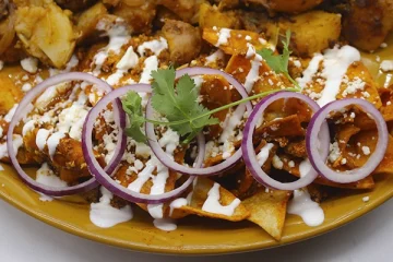 Mexican style chilaquiles breakfast plate with a side of potato salad, topped with sour cream