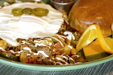 A hearty breakfast platter featuring chorizo, jalapeño and tomato with queso fresco, topped with cream and bread